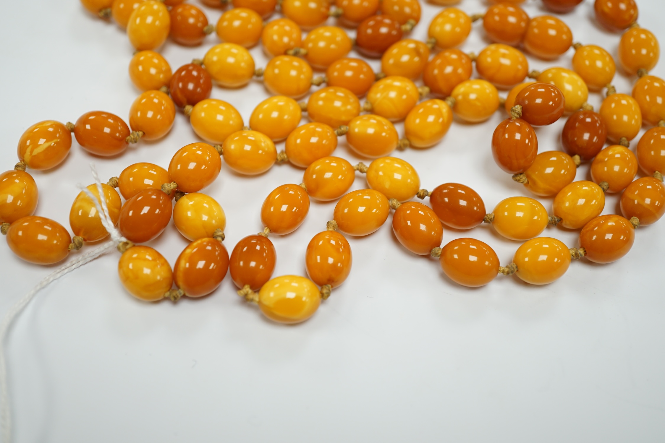 A long single strand oval amber bead necklace, 156cm, gross weight 89 grams.